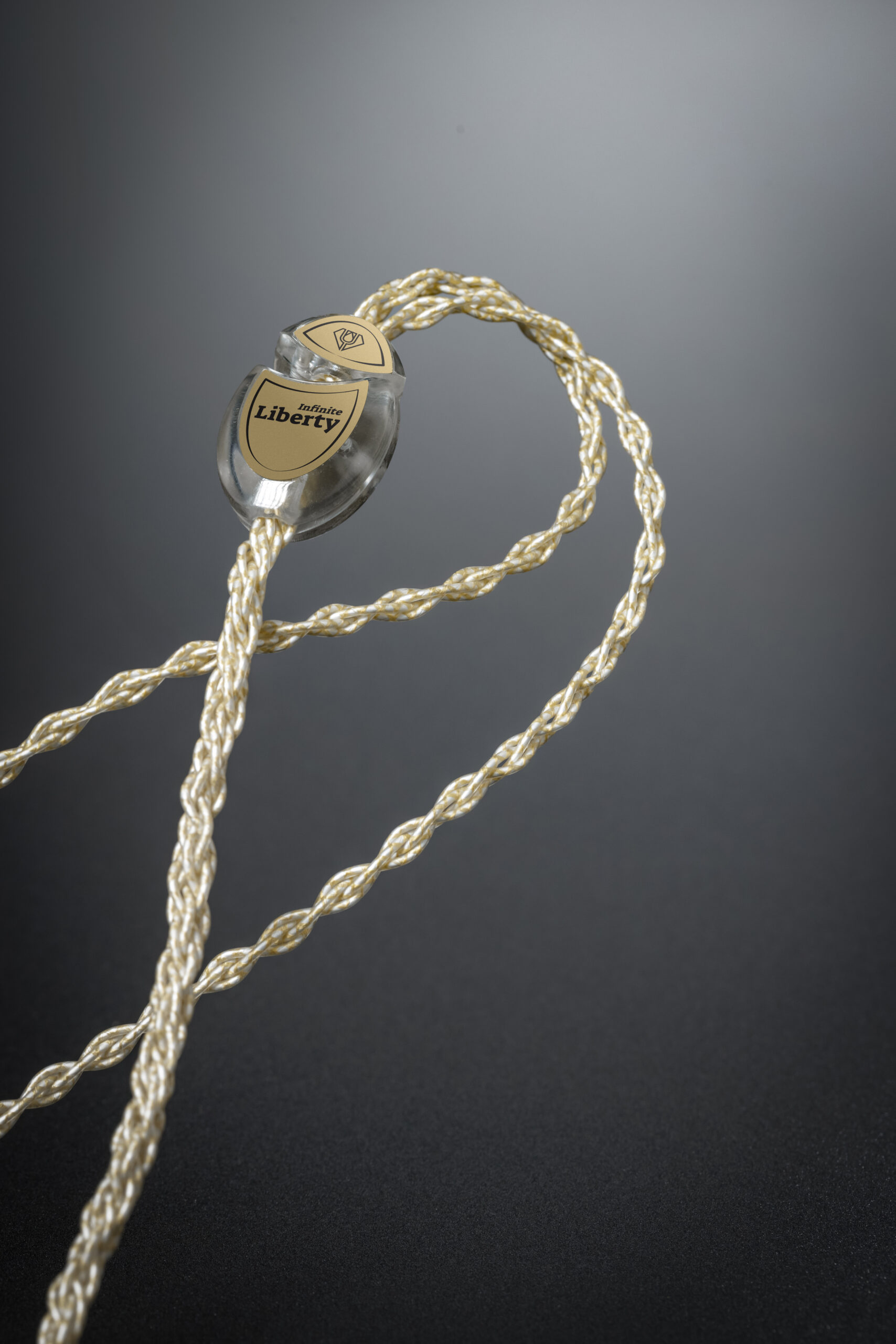 Crystal Cable Infinite Liberty — a hand-braided gold and silver cable looped across a dark surface, its connector resting in the curve.